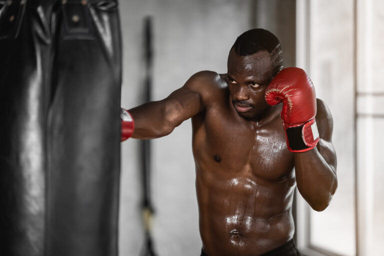 African man training in gym and fists his boxing bag fists. Sport man training at gym, fitness, boxing, success, workout and power